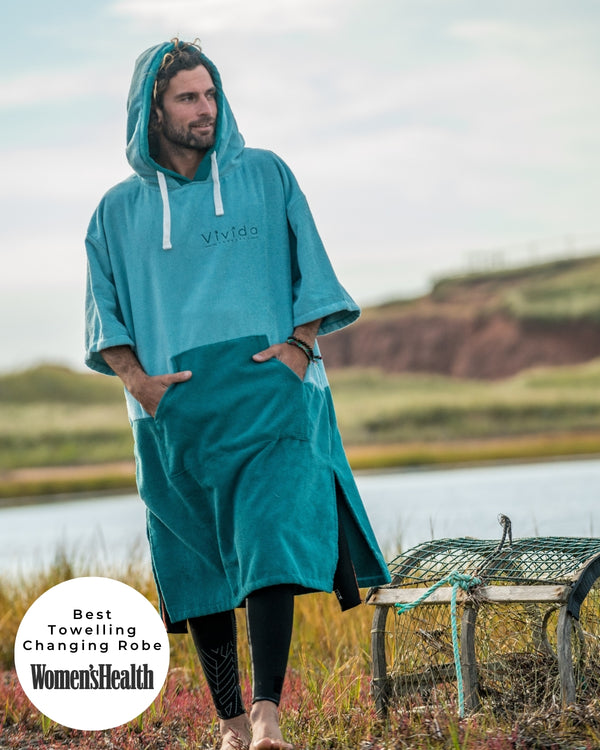 Lead_women - Woman wears a Vivida Original Adult Poncho Towel Changing Robe - Turquoise Teal / Pacific Teal. Sticker reads Women's Health Best Towelling Changing Robe