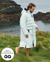 Lead_men - Man wearing a Vivida Lifestyle All Weather Puffer Changing Robe, Matcha Green Drying Robe for swimming standing on rocks. Sticker: Best Premium Changing Robe - The Independent.