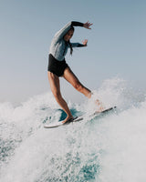 Woman wearing a Vivida Linda Reversible Shortie Neoprene Wetsuit - Graphite / Map of Dreams surfing