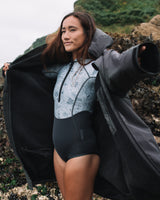 Lead_women2 - Woman putting on the All Weather Sherpa Changing Robe - Fossil Grey with hood