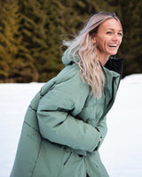 Woman walking in the snow wearing a Vivida All Weather Puffer Changing Robe in Aventurine Green