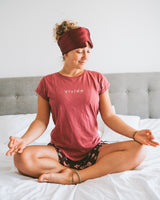 Woman meditating wearing a Vivida Silk Blackout Eye Mask - Burgundy Berry