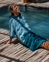 Woman wears a Vivida Original Adult Poncho Towel Changing Robe - Turquoise Teal / Pacific Teal. Sticker reads Women's Health Best Towelling Changing Robe