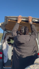 Woman dances in her Vivida Lifestyle Puffer Changing Robe on a surf trip in a campervan