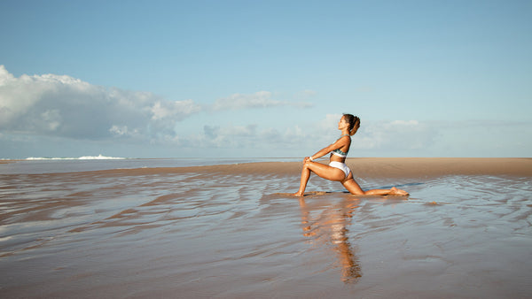 Woman doing yoga on a beach in sustainable swimwear