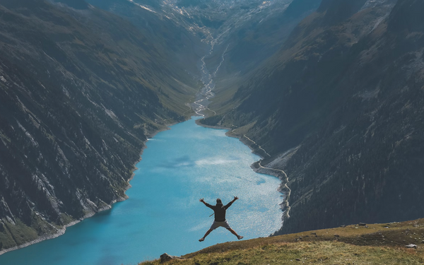 Man jumping for joy on a mountain above a river