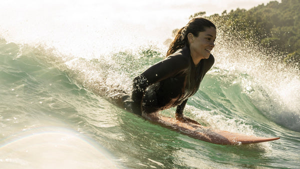 How to connect to nature through surfing - woman riding a wave on a surfboard