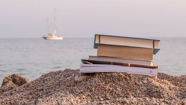 A stack of books on a beach - best books about swimming