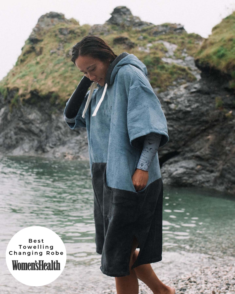 Lead_women - Woman wears a Vivida Original Poncho Towel Changing Robe - Mineral Blue / Anthracite Grey. Sticker reads Women's Health's Best Towelling Changing Robe