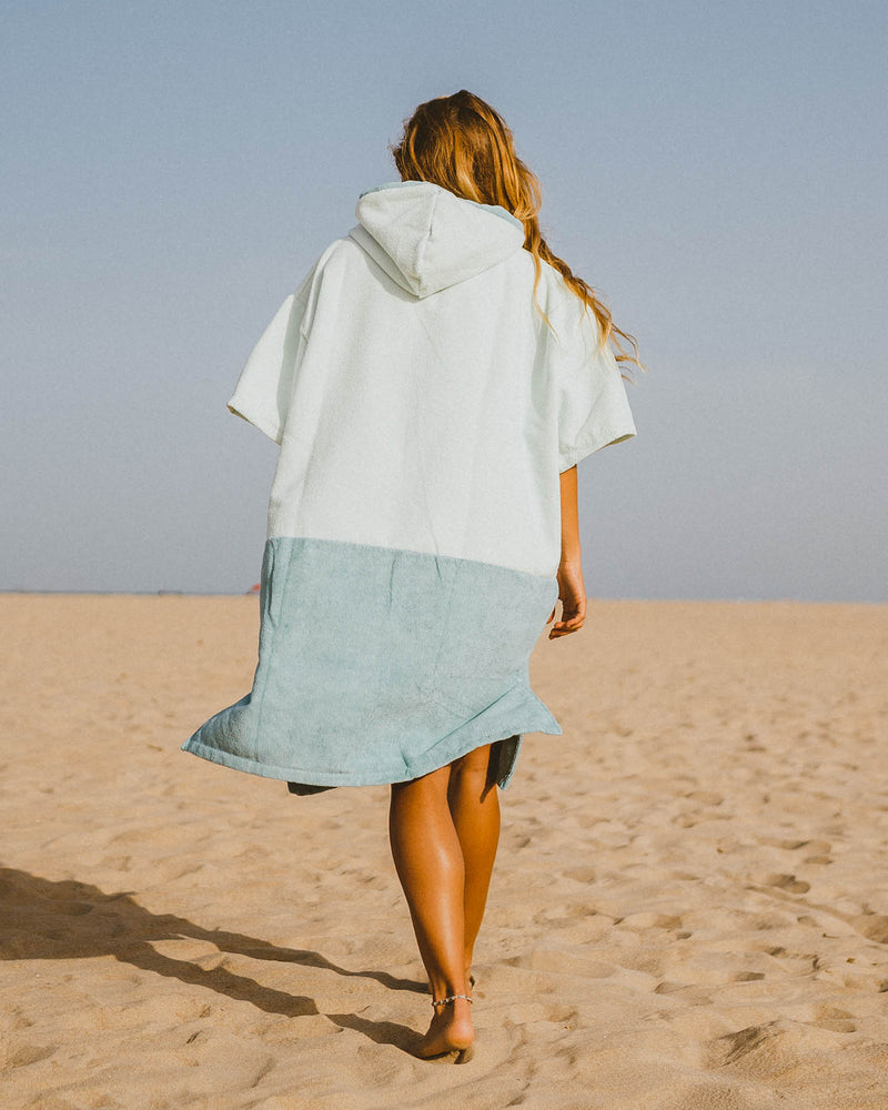 Woman wears a Vivida Original Poncho Towel Changing Robe - Seafoam Green