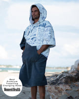 Lead_men - Man wearing a Vivida Premium Adult Poncho Towel Changing Robe - Cloud Blue Map of Dreams. Sticker reads Women's Health's Best Premium Towelling Changing Robe