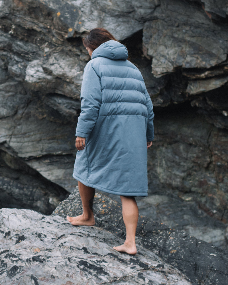 Woman from the back wearing a Vivida All Weather Puffer Changing Robe in Mineral Blue