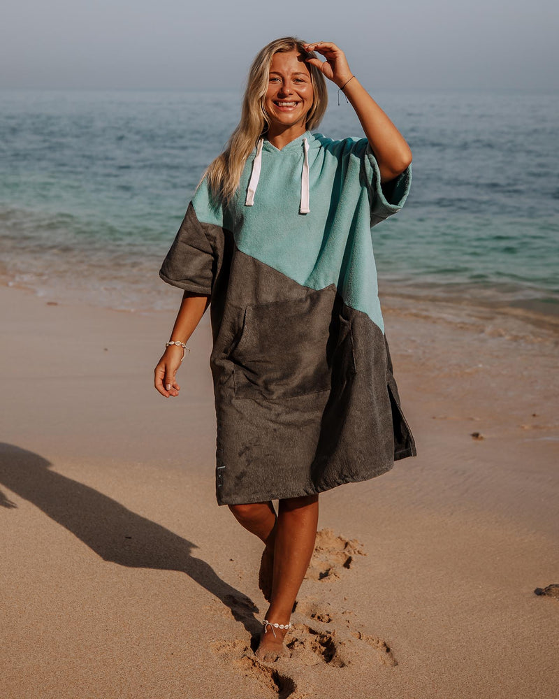 Woman walks in a Vivida Premium Poncho Towel Changing Robe - Turquoise Teal / Olive Grey