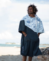 Man drying off wearing a Vivida poncho towel on the beach in the summer 