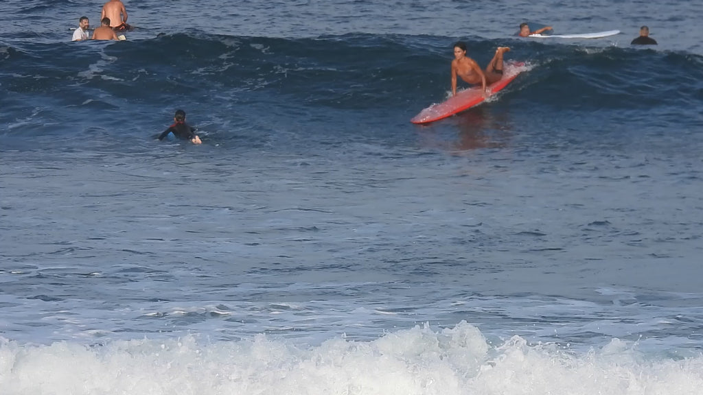 Woman surfing wearing the Vivida Hermosa Bikini Top and Nefeli Bikini Bottoms